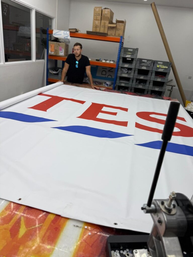 Finishing a Tesco logo banner in the workshop